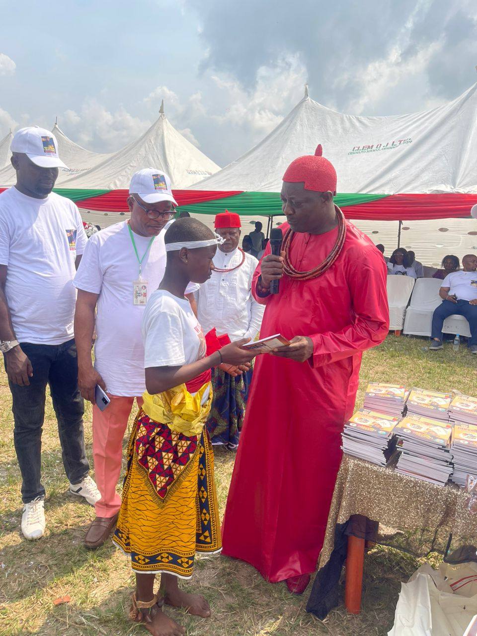 Student receiving exercise books from traditional ruler